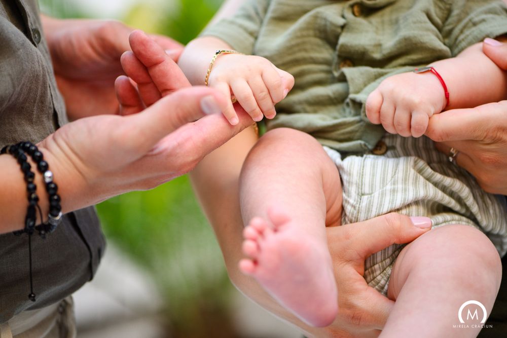 Close-up of tiny baby feet being held by adult hands with bracelets.