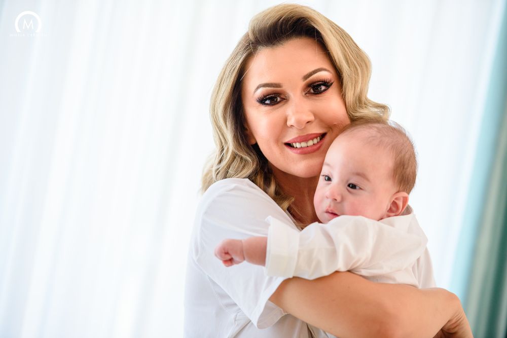 A sweet tender moment between parent and infant against a light background.