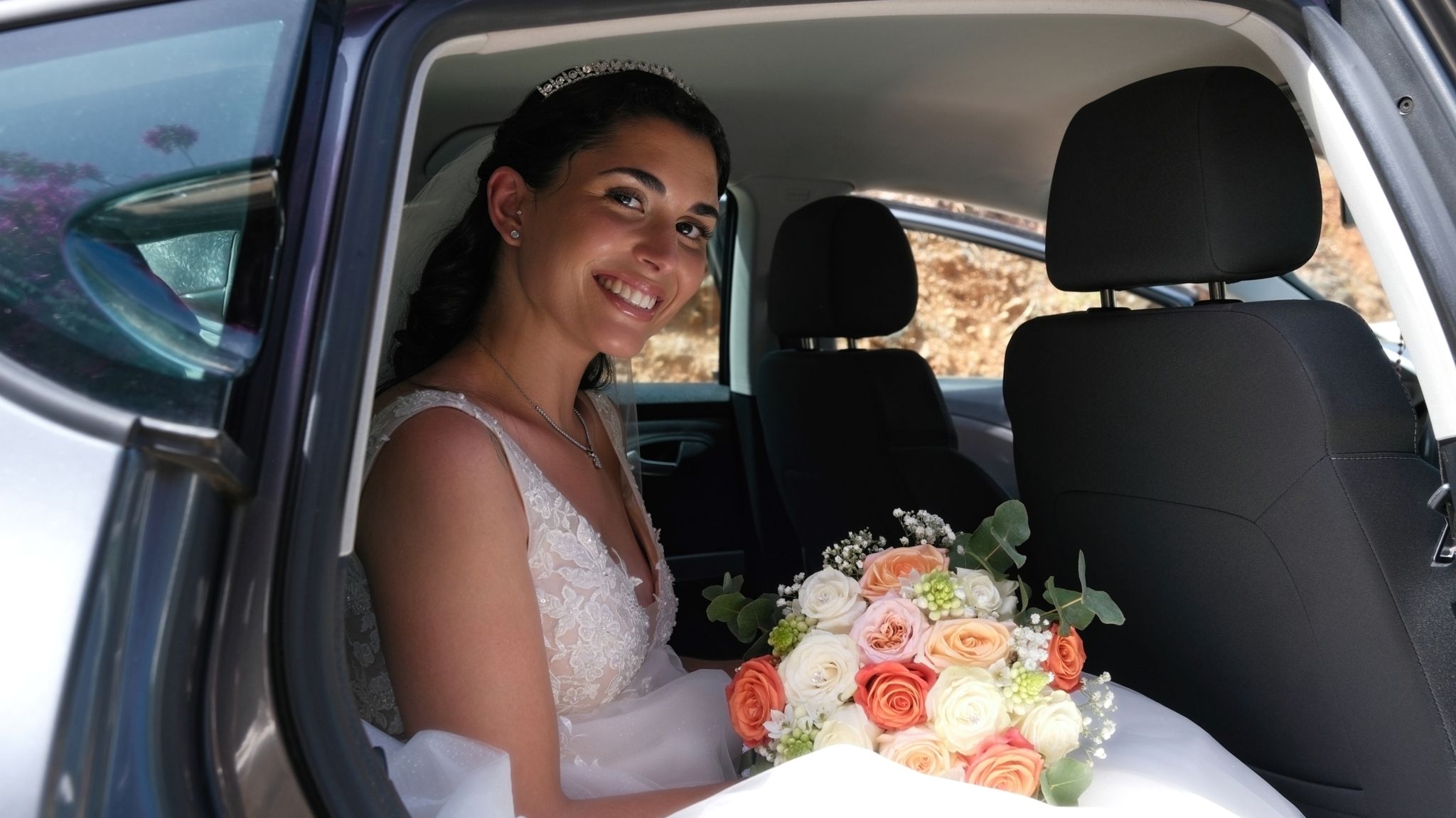 A bride sitting inside a car on her wedding day
