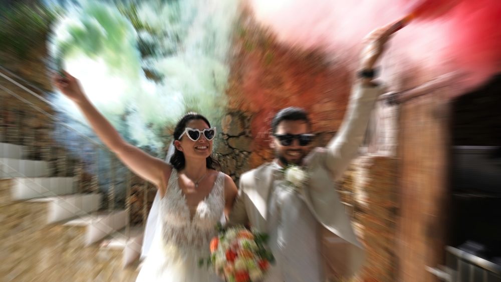 Wedding couple  with trendy sunglasses and colourful smoke flares.