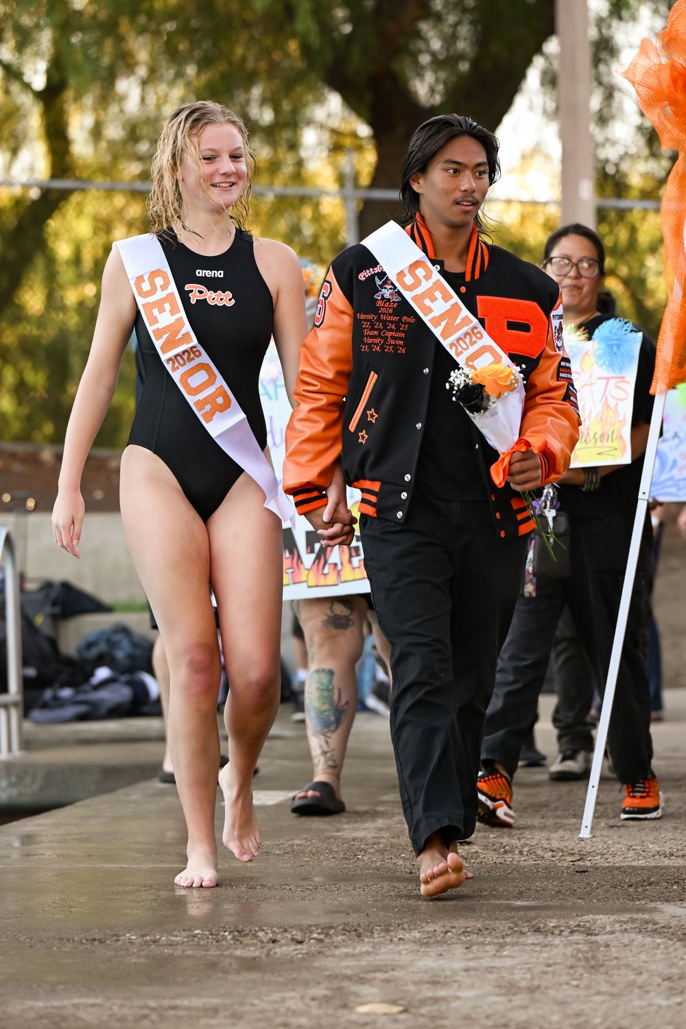 Athletes in black and orange uniforms running together during an outdoor event.