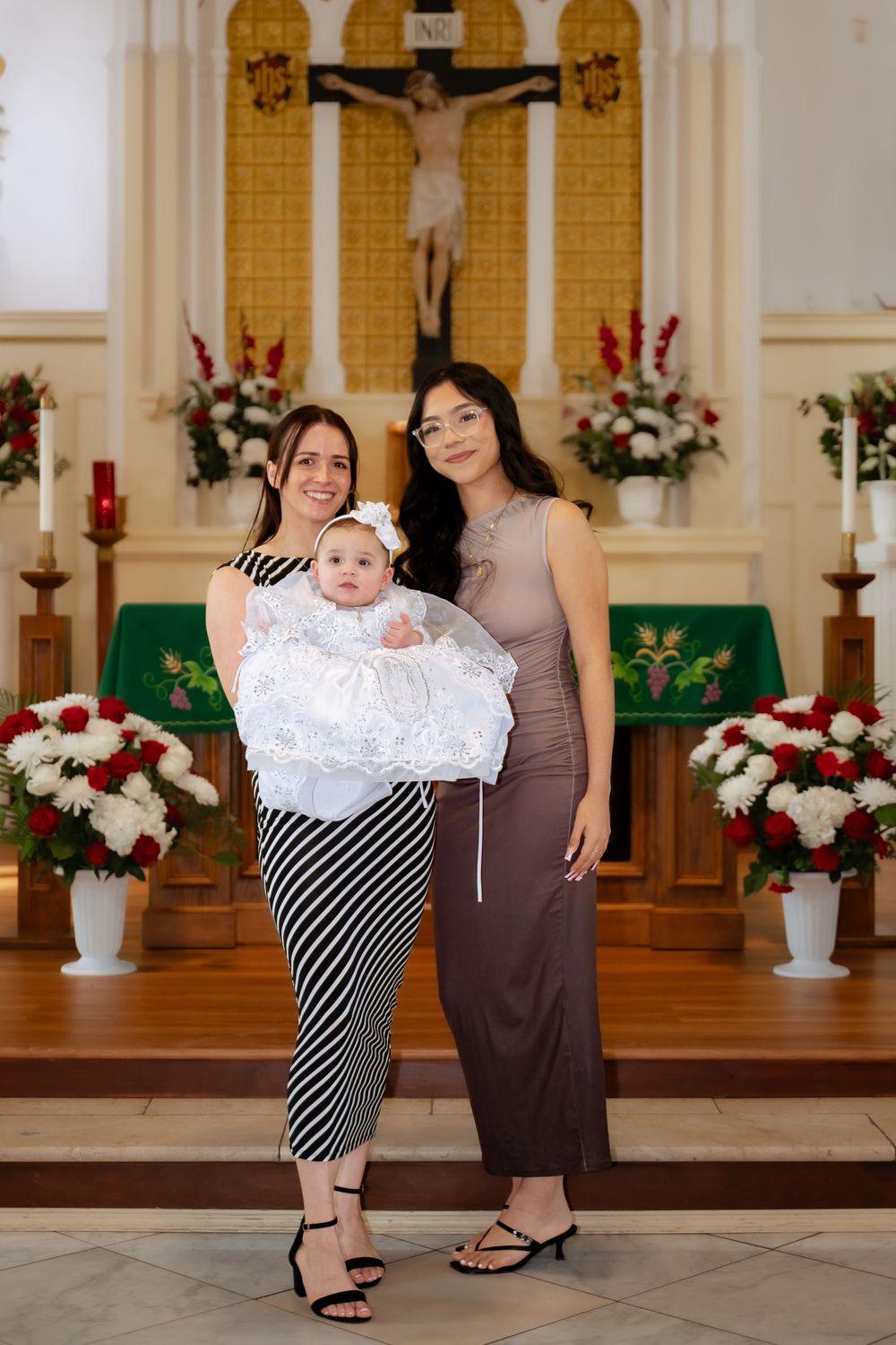 People in formal wear posing together in a church with floral decorations.
