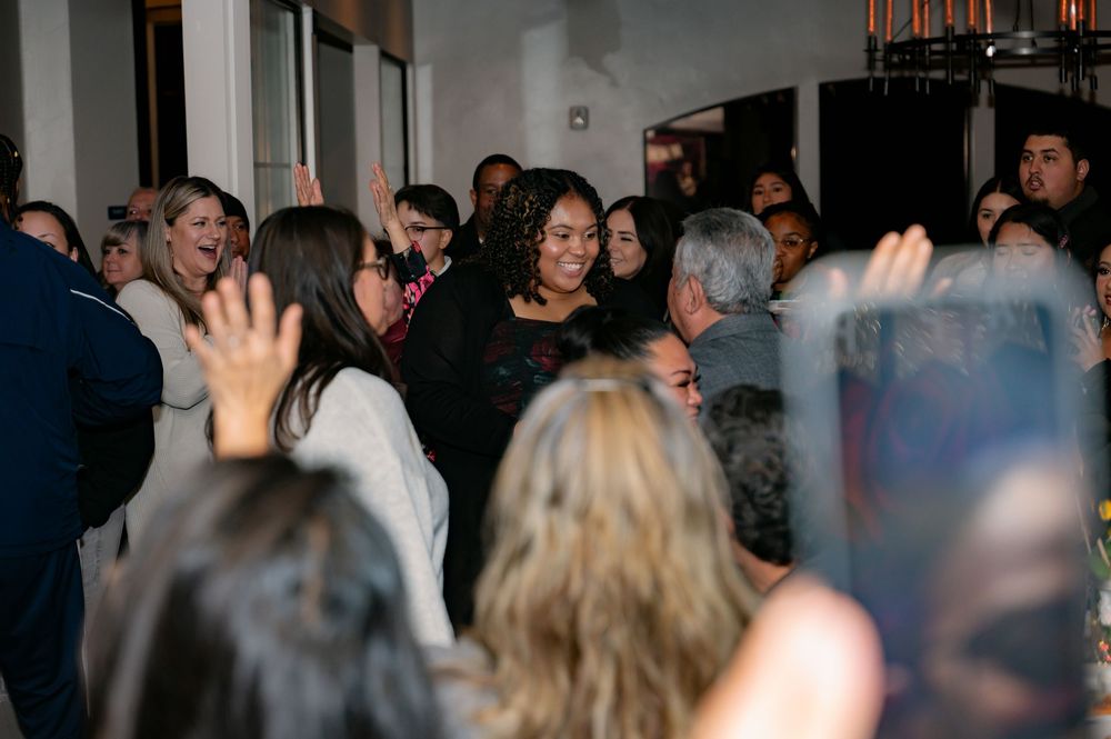 Crowd of people gathered in an indoor space with raised hands.