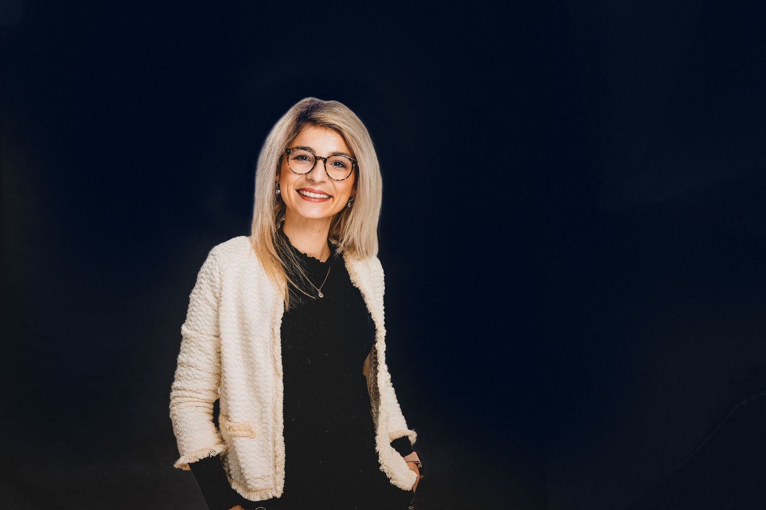professionelles Businessfoto einer blonden Frau mit Brille und lässiger Haltung freundlich lächelnd im Fotostudio Aurelia Schulz Arolsen