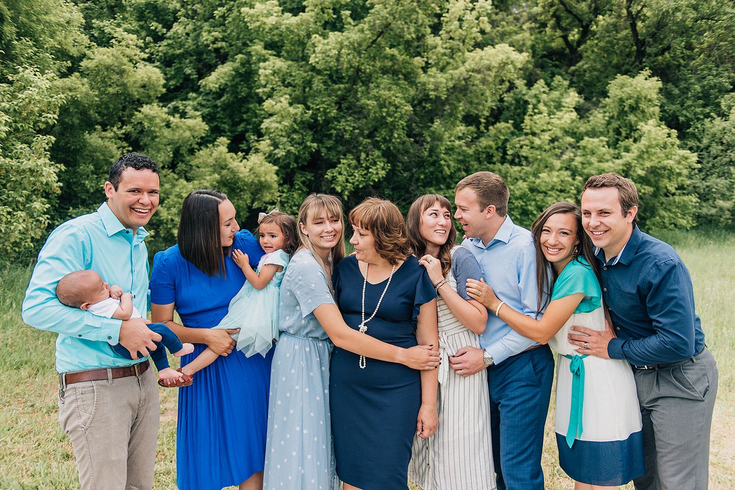 Large group poses together outdoors while sharing joyful moments in casual summer attire.