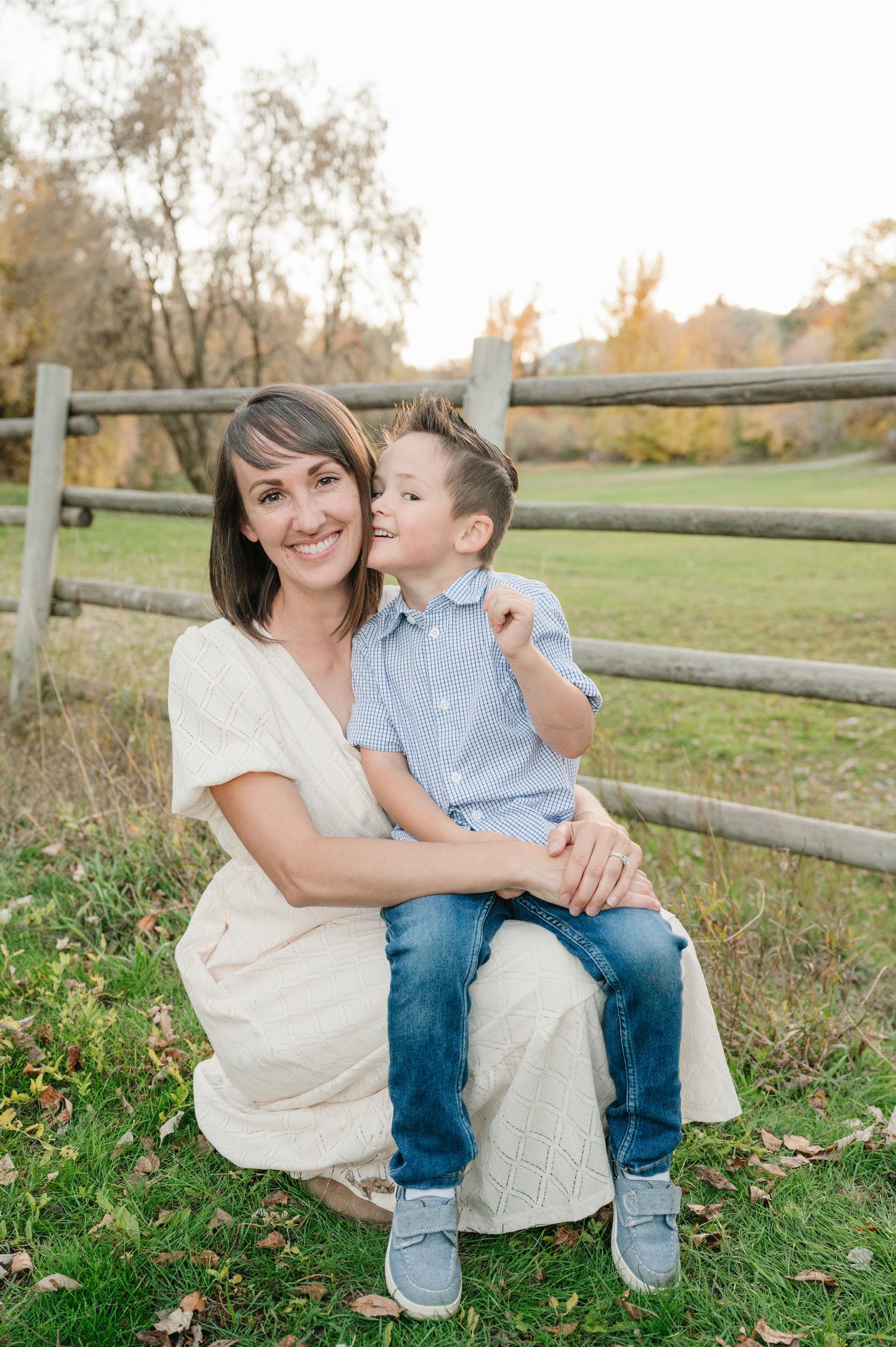 Sweet moment captured between parent and child by wooden fence in fall setting.