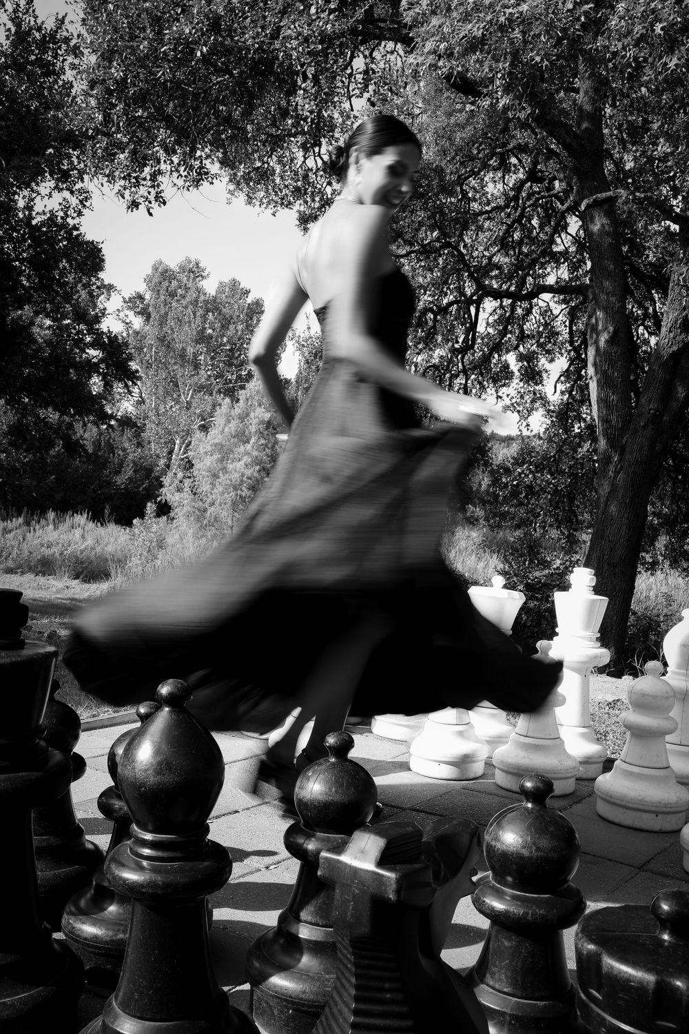 Motion-blur photograph capturing a twirling figure on a giant outdoor chess board.