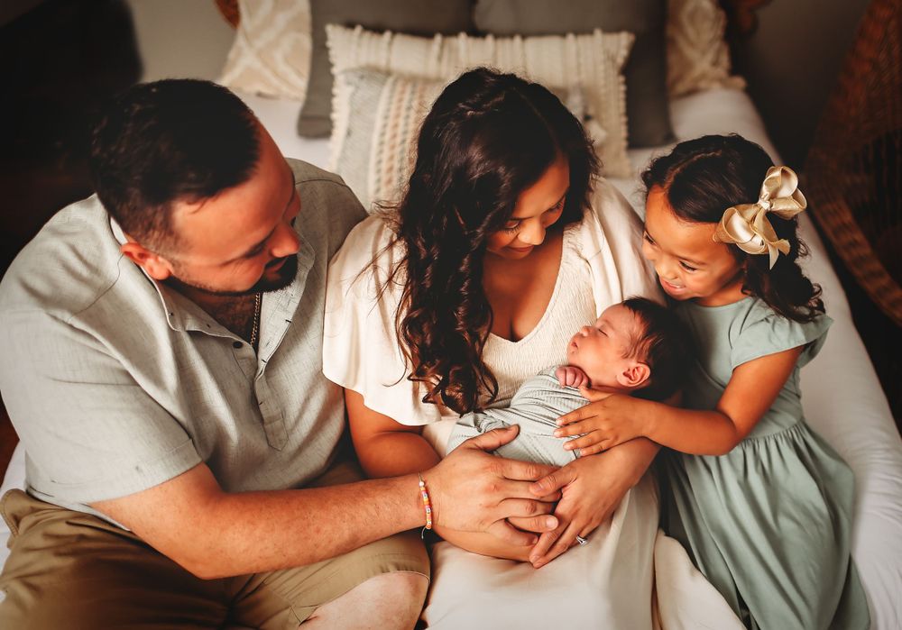 Mom, dad and big sister holding baby brother for photo session