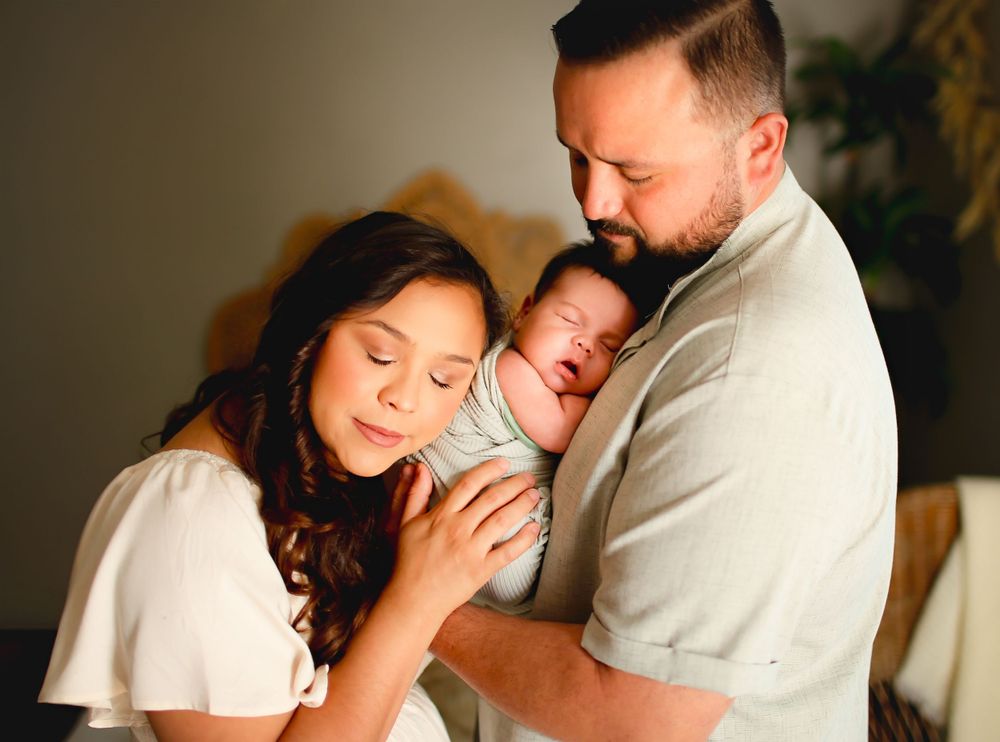 dad holding baby on chest and mom laying on baby
