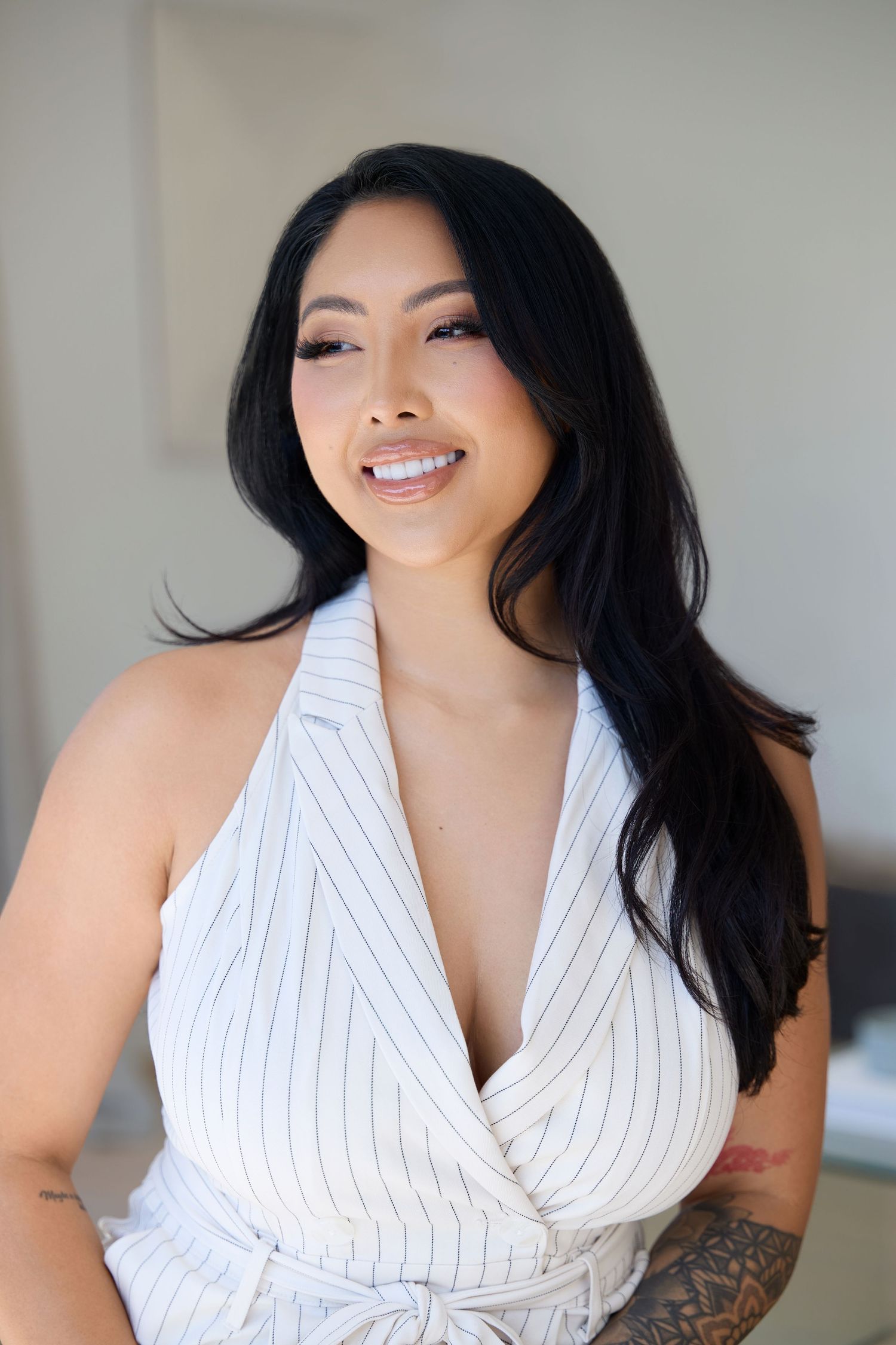 Portrait of woman in white pinstripe wrap top with long dark hair and natural makeup.