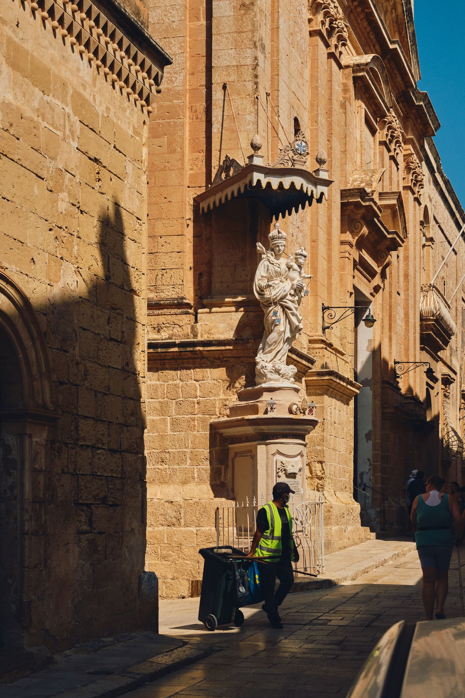 Ancient stone street with ornate statue and architectural details in a historic Mediterranean city.