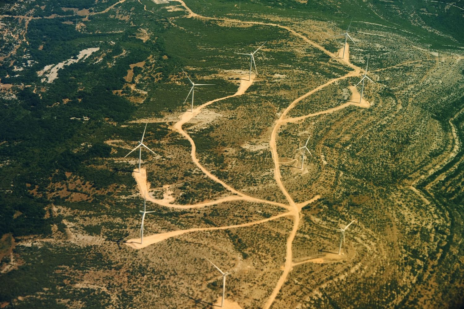 Aerial view of winding dirt roads cutting through rugged mountain terrain.
