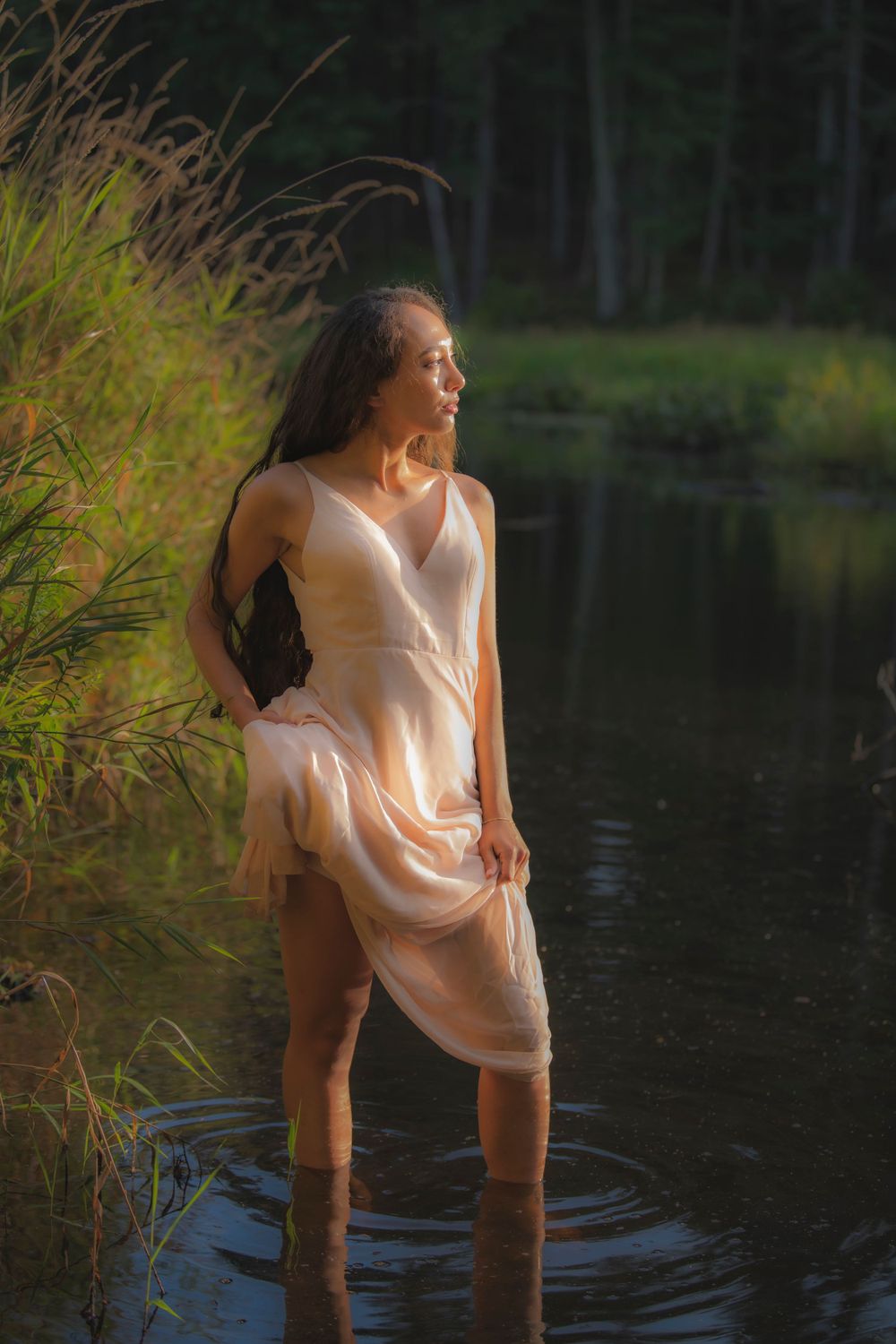 Elegant pose captured in soft light as figure stands in peaceful forest pond.