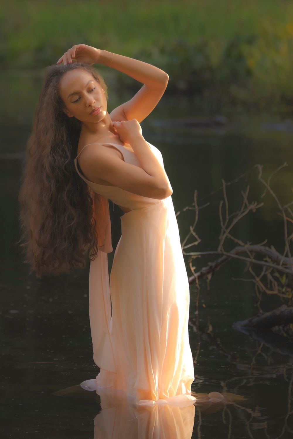 Dreamy water portrait with flowing dress and natural light creating ethereal mood.