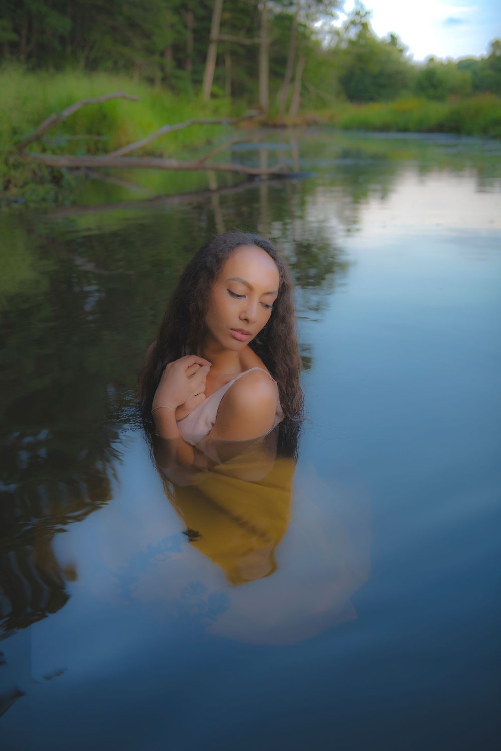 Artistic water portrait with moody lighting and tranquil forest backdrop.