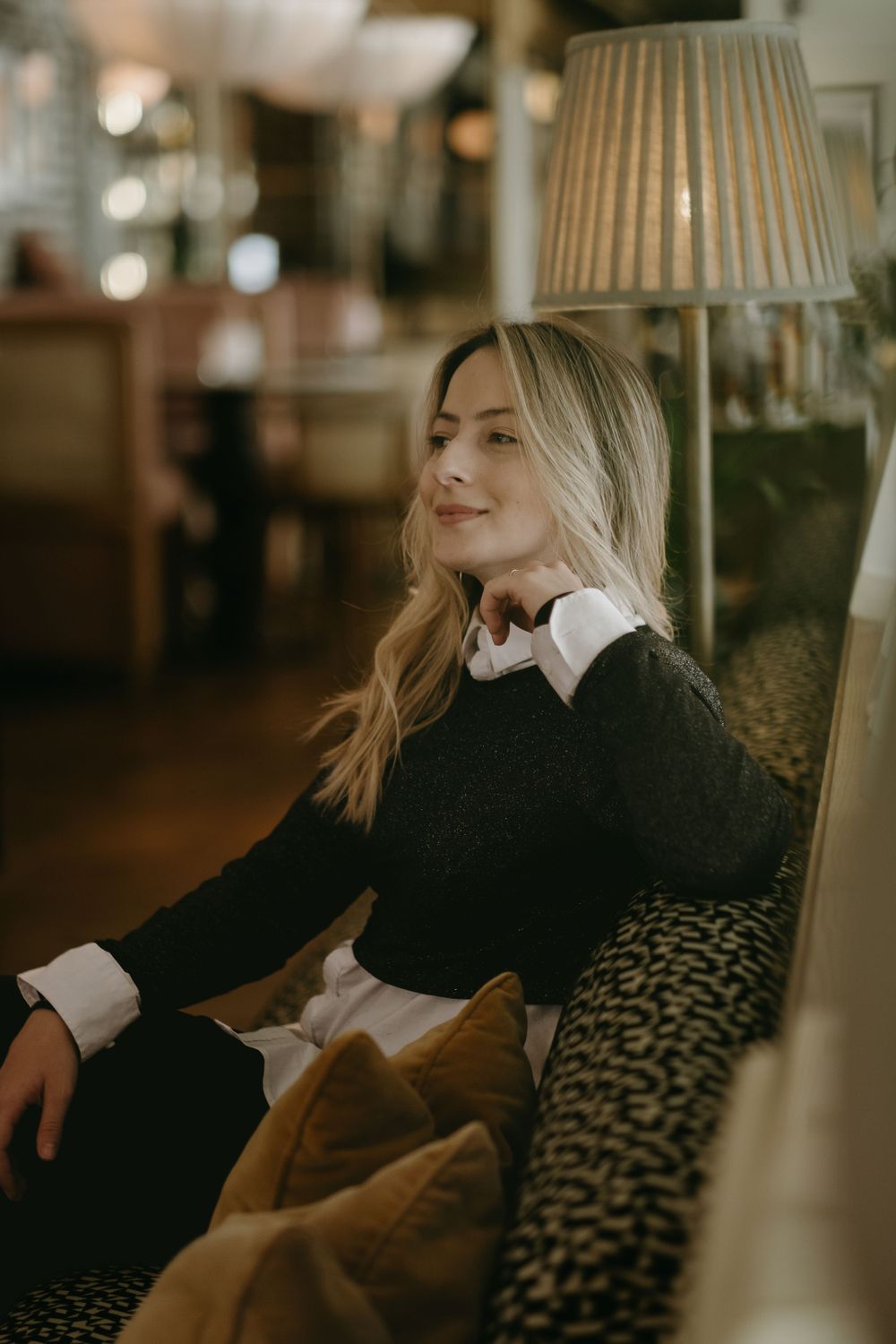 a woman sitting on a sofa looking away while being captured by portrait photographer in Stockholm