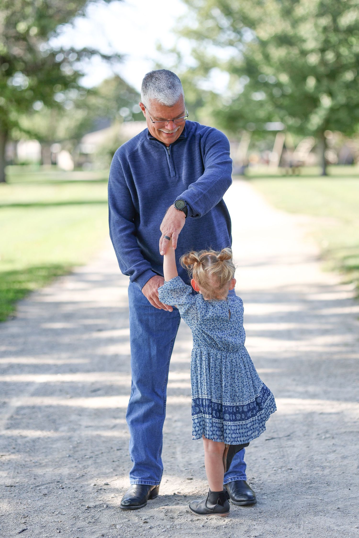 Sweet moment captured between adult and child dancing on park pathway.