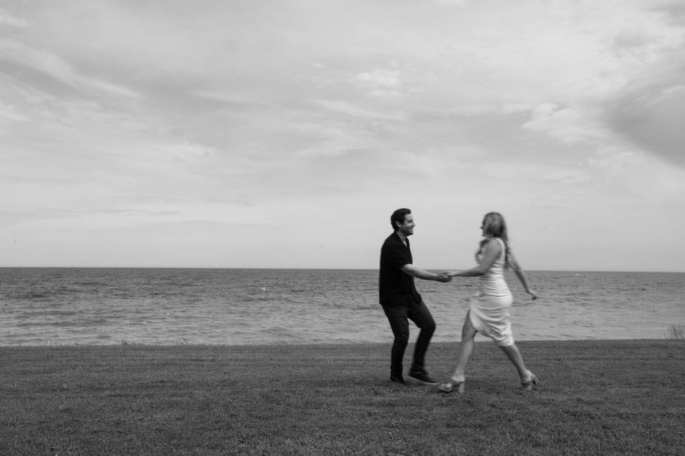 Black and white photo of couple dancing by the ocean.