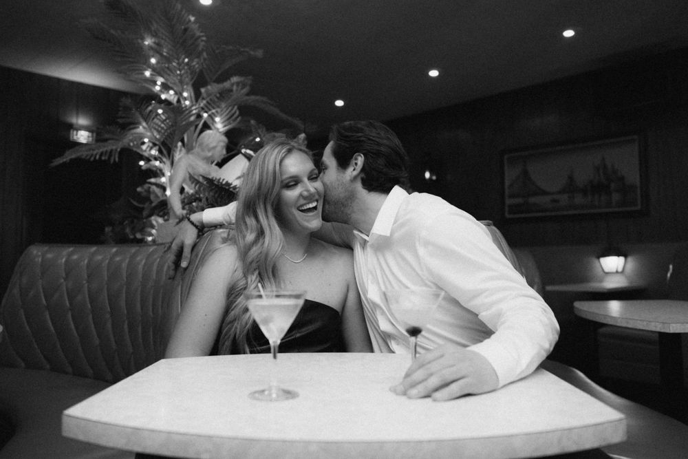 Candid black and white photo of joyful couple sharing laughter at romantic dinner.