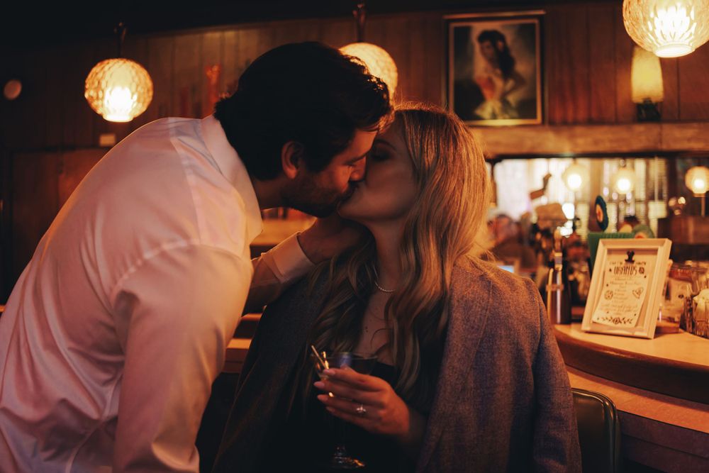 Romantic couple sharing an intimate moment at a dimly lit bar with vintage lanterns.