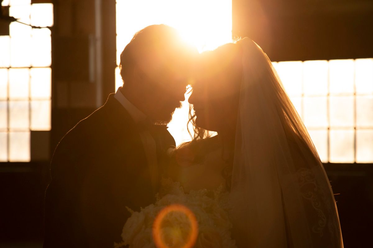Silhouettes of people against bright window light creating a dramatic wedding scene.