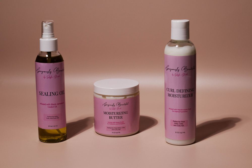 Pink beauty product collection featuring moisturizing spray, cream, and lotion bottles on a peach background.