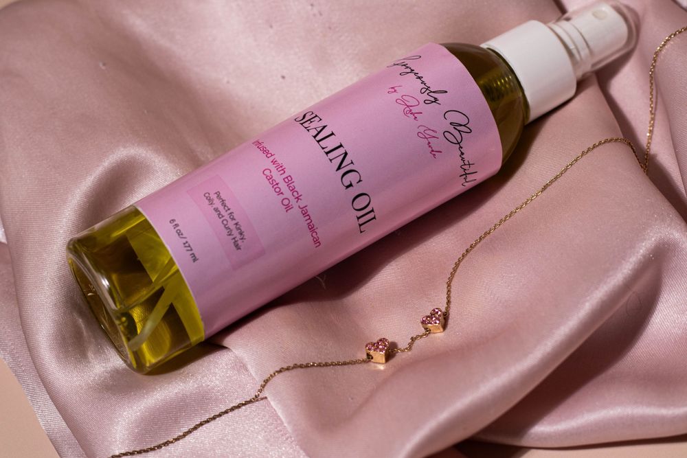 Pink beauty product bottle lying on silky fabric with a delicate necklace.