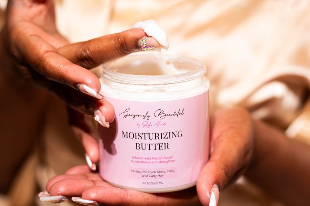 Hands holding a pink jar of moisturizing butter cream product.