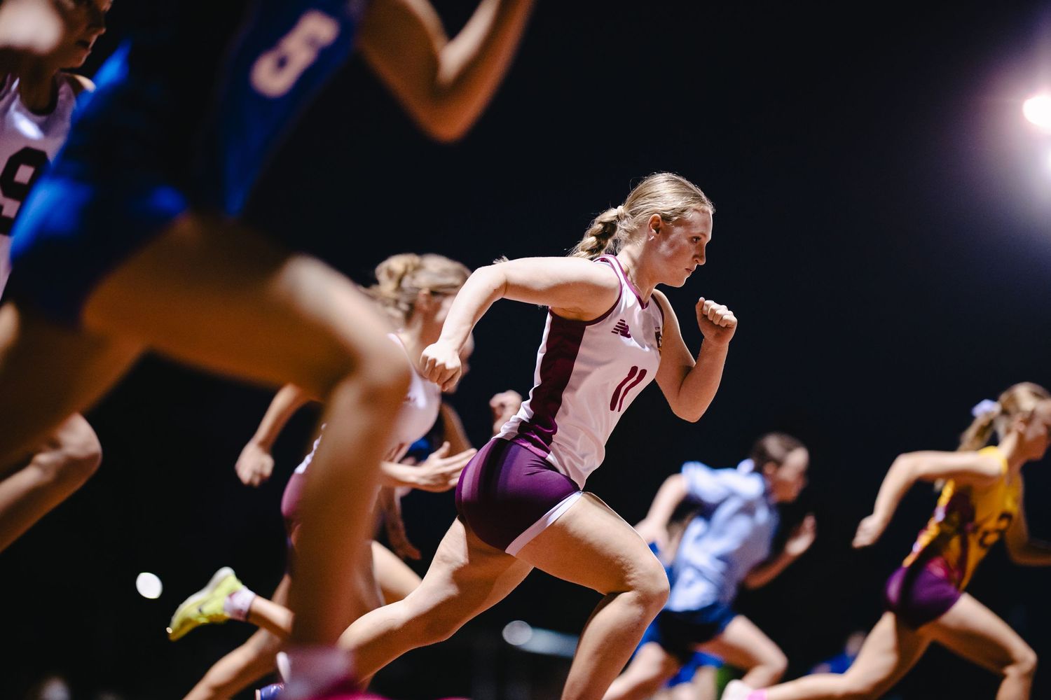 Athletes sprinting on track during competitive night race.