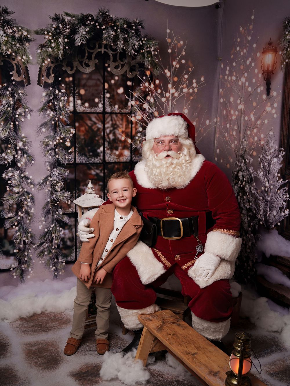 A festive Christmas photo session featuring Santa Claus and a child in a cozy winter wonderland setting with sparkling lights.