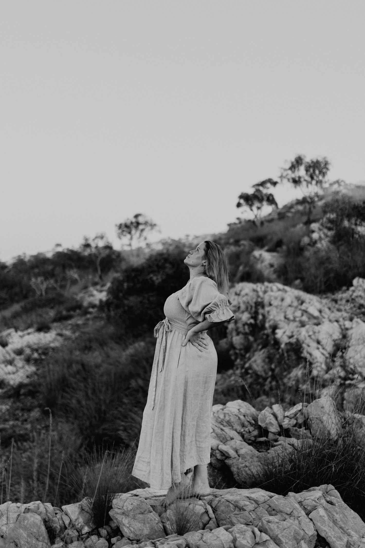 Black and white image of woman embracing wind while standing on cliffs at Lake Moondarra, Mount Isa
