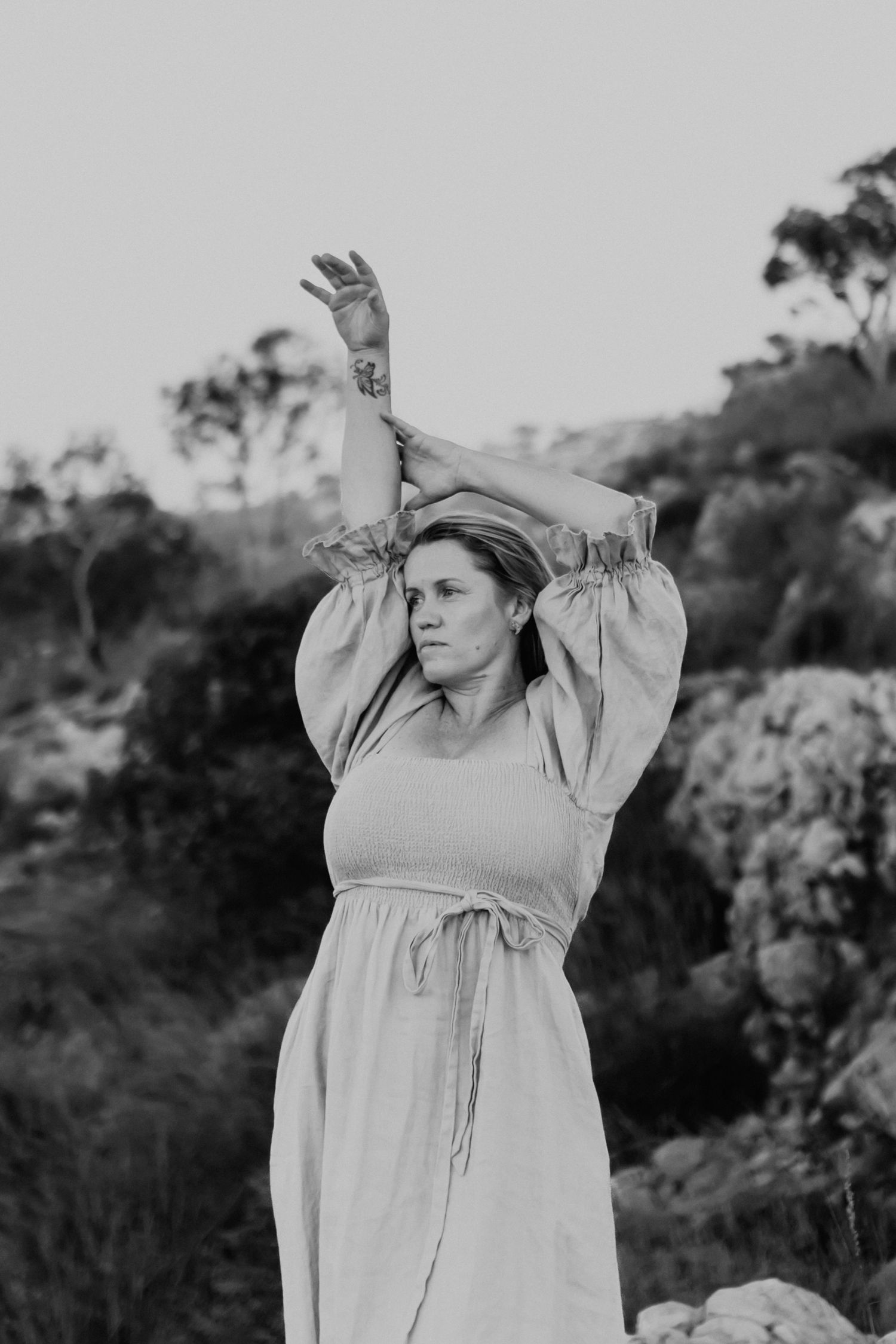 Black and white shot of woman embracing wind on cliffs at Lake Moondarra