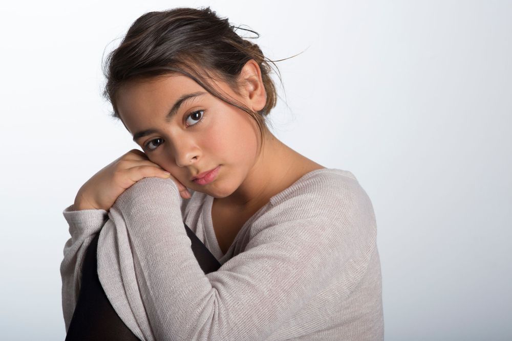 Portrait of someone in a beige sweater resting against their hand on white background.