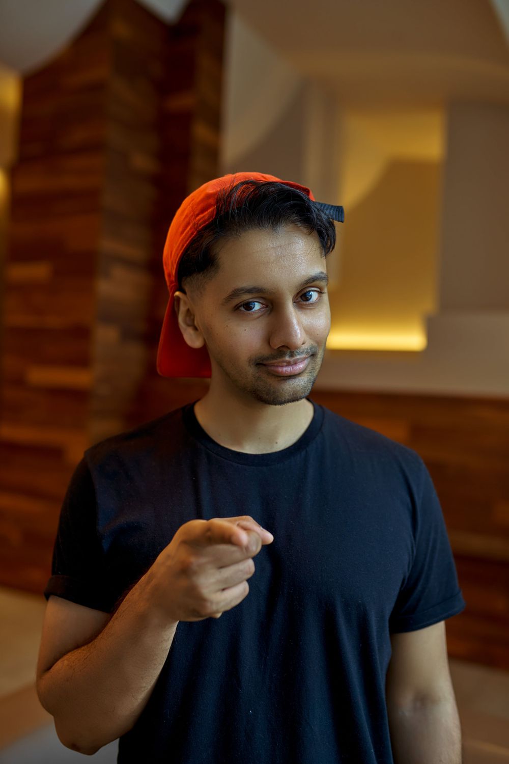 Casual portrait series featuring navy t-shirt and red baseball cap in indoor setting.