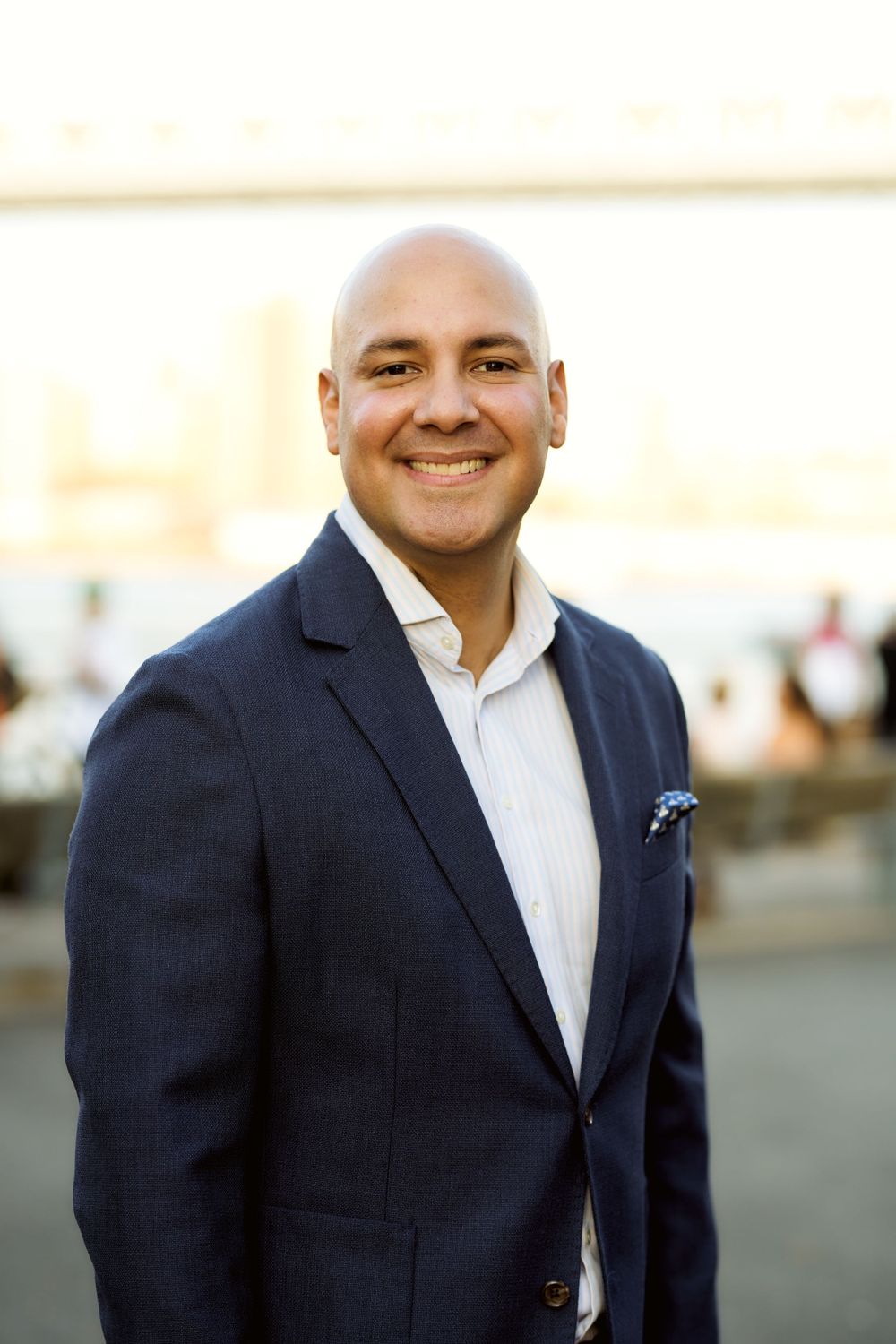 Professional headshots of businessman in navy blazer and white shirt outdoors.