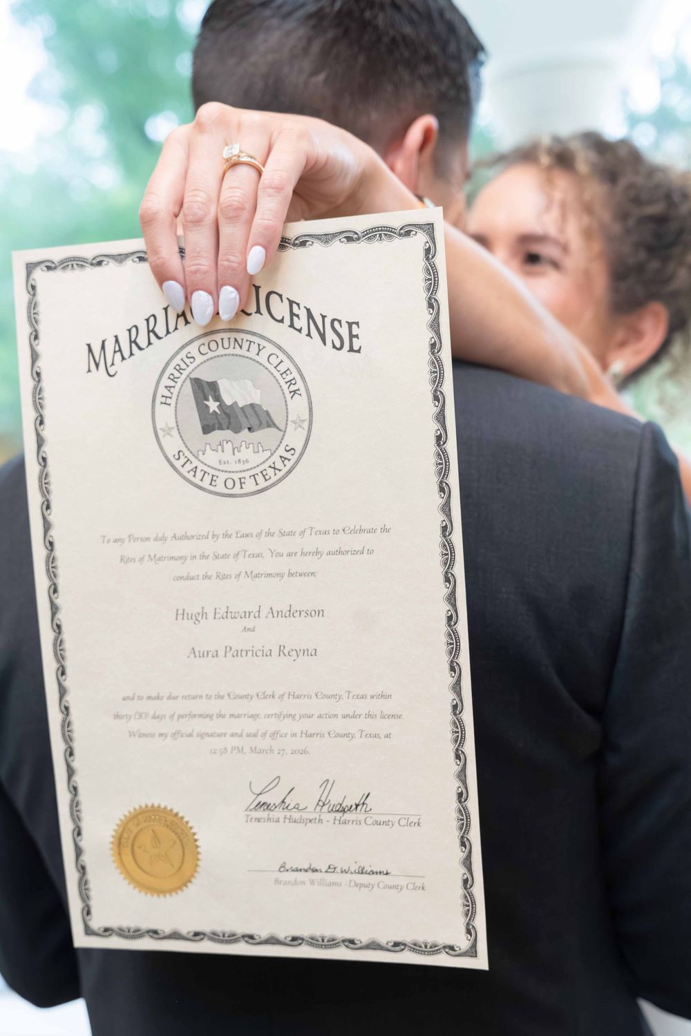 Couple holding Harris County Texas marriage license certificate after wedding ceremony.