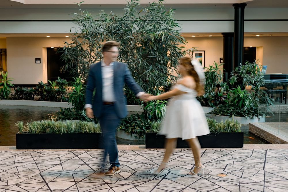 Couple dancing together in an indoor garden atrium with white dress and navy suit.