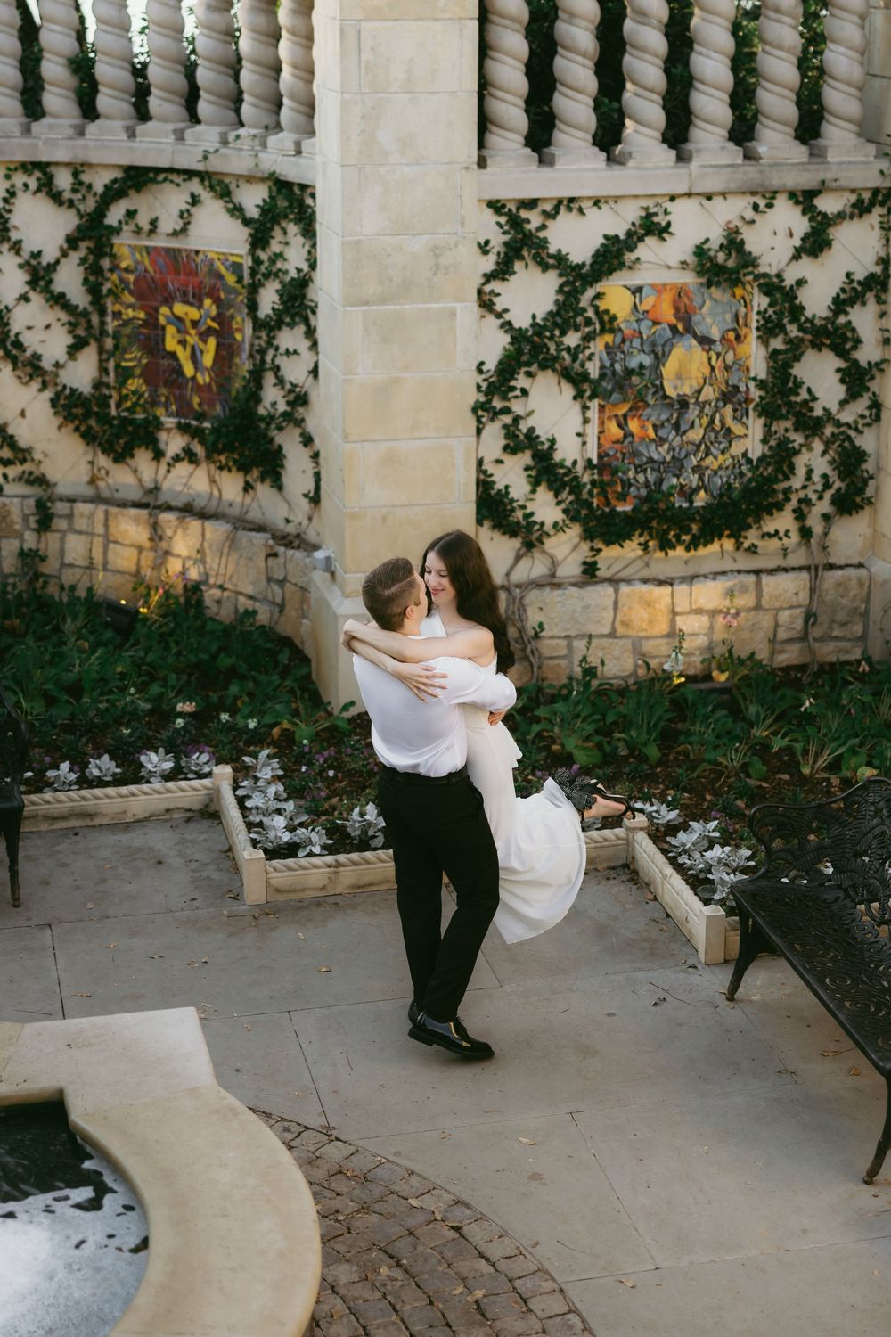 A romantic dance sequence in front of a stone wall with climbing vines shows a graceful dip movement.