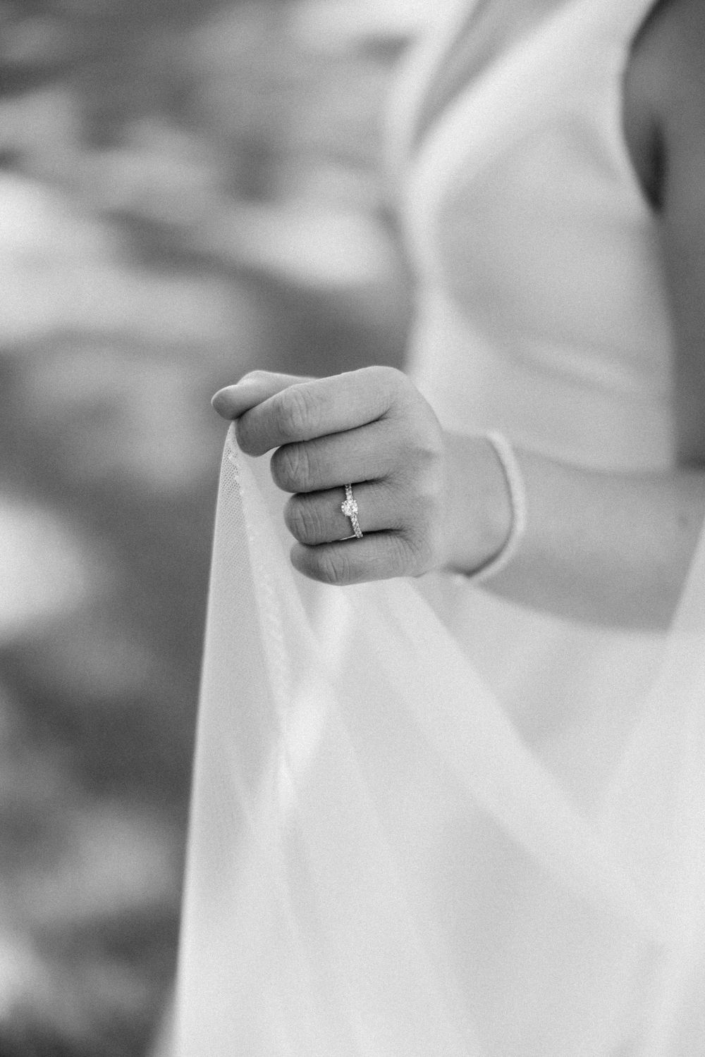 Black and white close-up image of hands wearing white gloves against a blurred background.