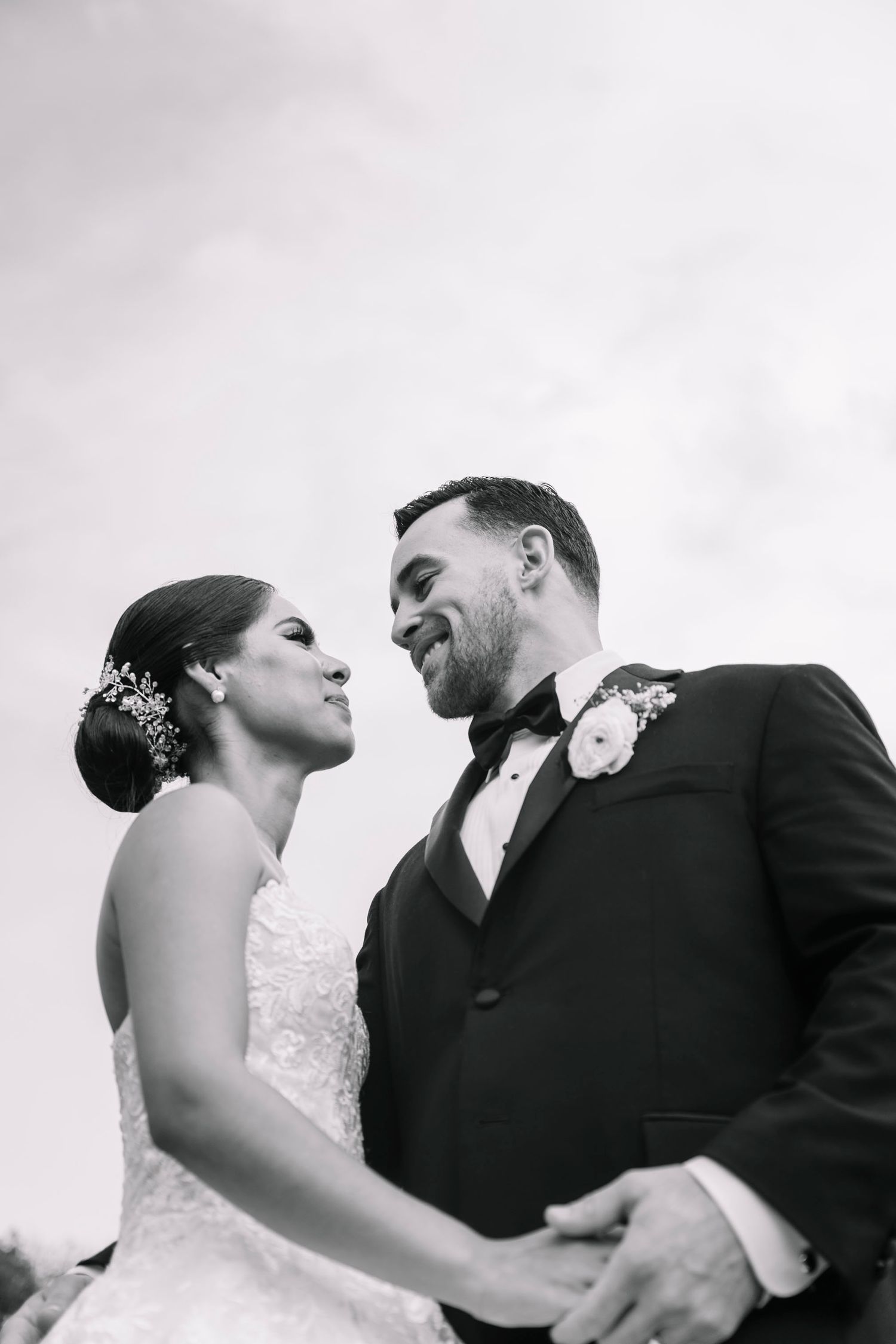 A black and white wedding portrait of a couple sharing an intimate moment outdoors.