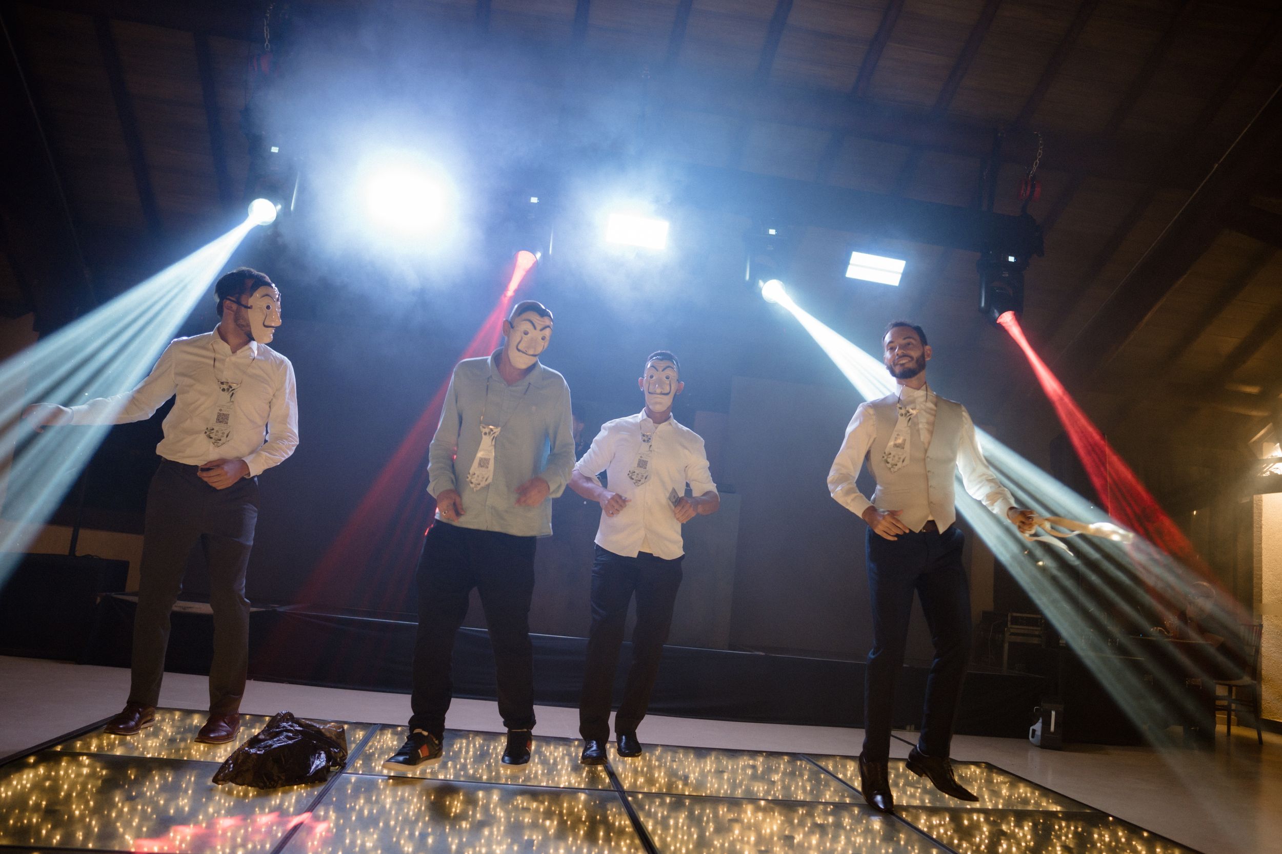 Musicians perform on stage with dramatic lighting and beams creating an atmospheric concert environment.