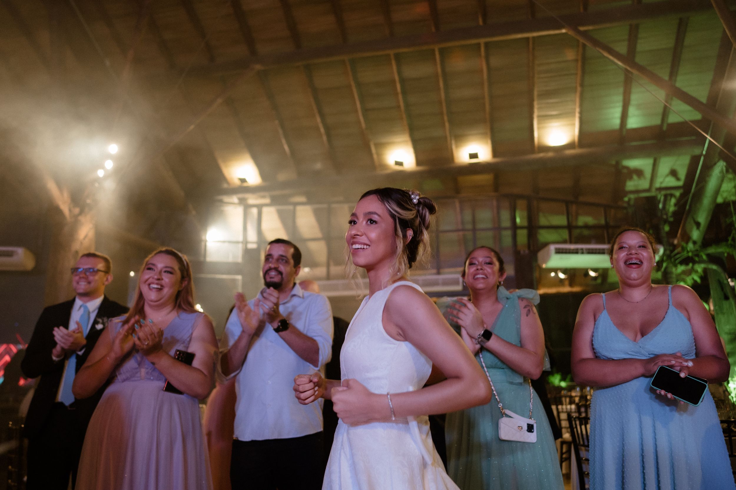 Wedding party members stand in a line during reception wearing formal attire.