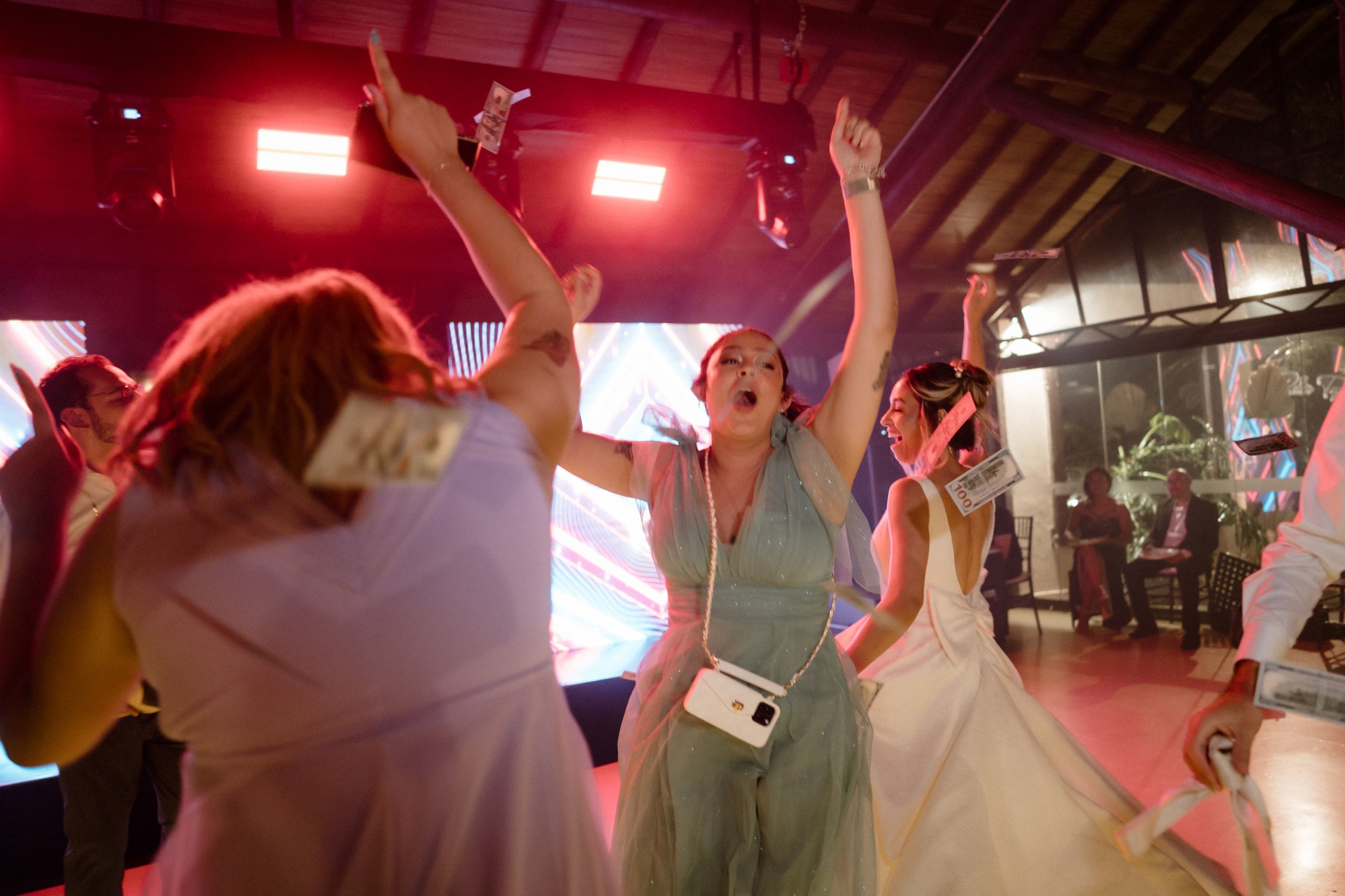 People dancing energetically on a colorful illuminated dance floor at a celebration.