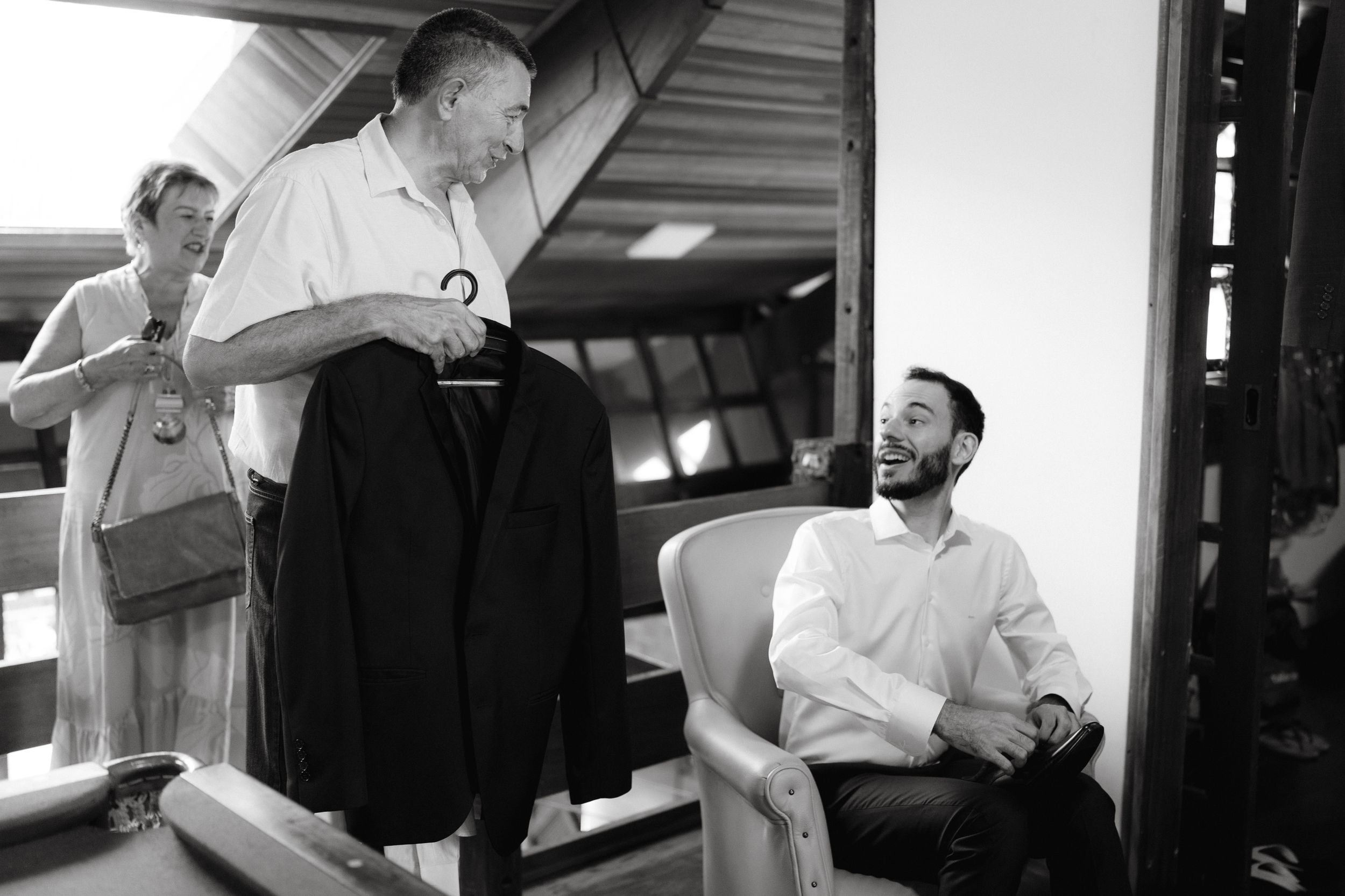 Black and white photo of people preparing formal attire before an event.