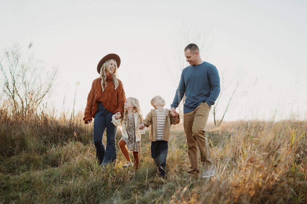 Group walking together through a golden field at sunset with tall dry grass.