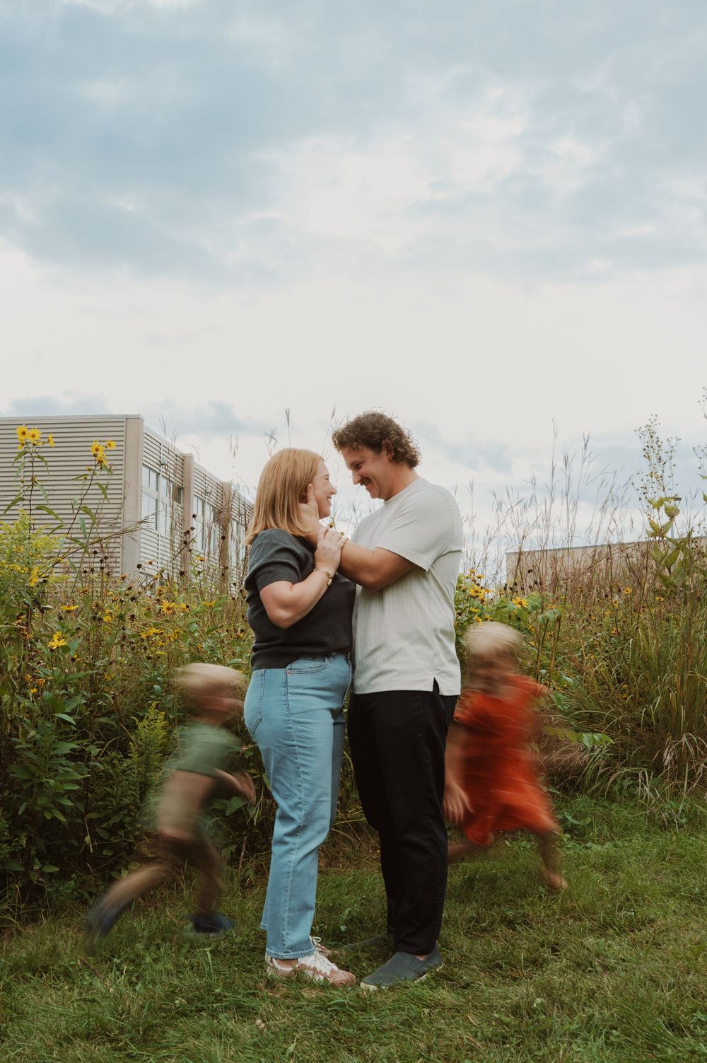 A series of motion blur photos showing people dancing and spinning in a grassy field with wildflowers at sunset.
