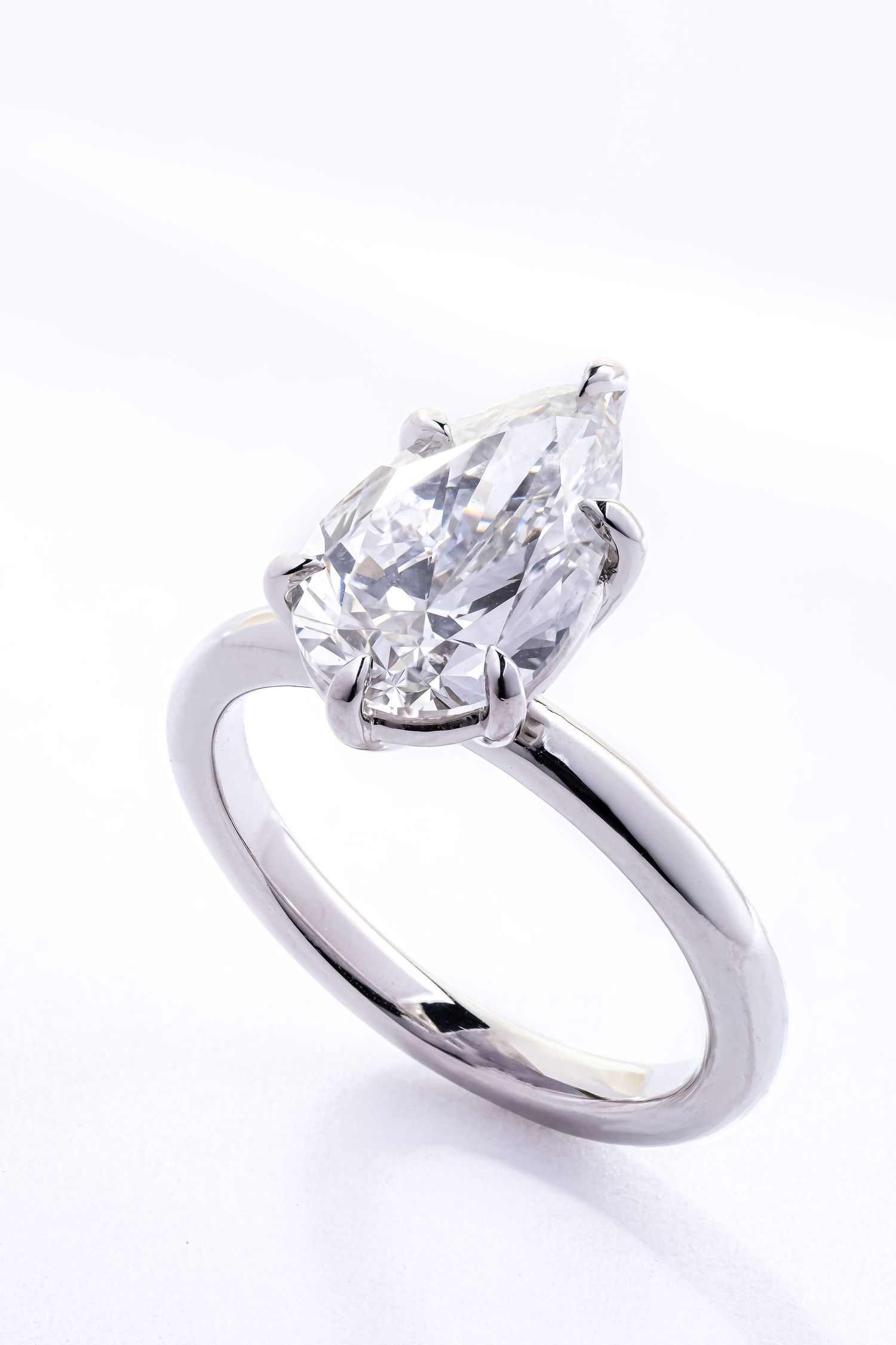 A classic solitaire engagement ring with a pear-shaped diamond in a simple platinum or white gold setting.