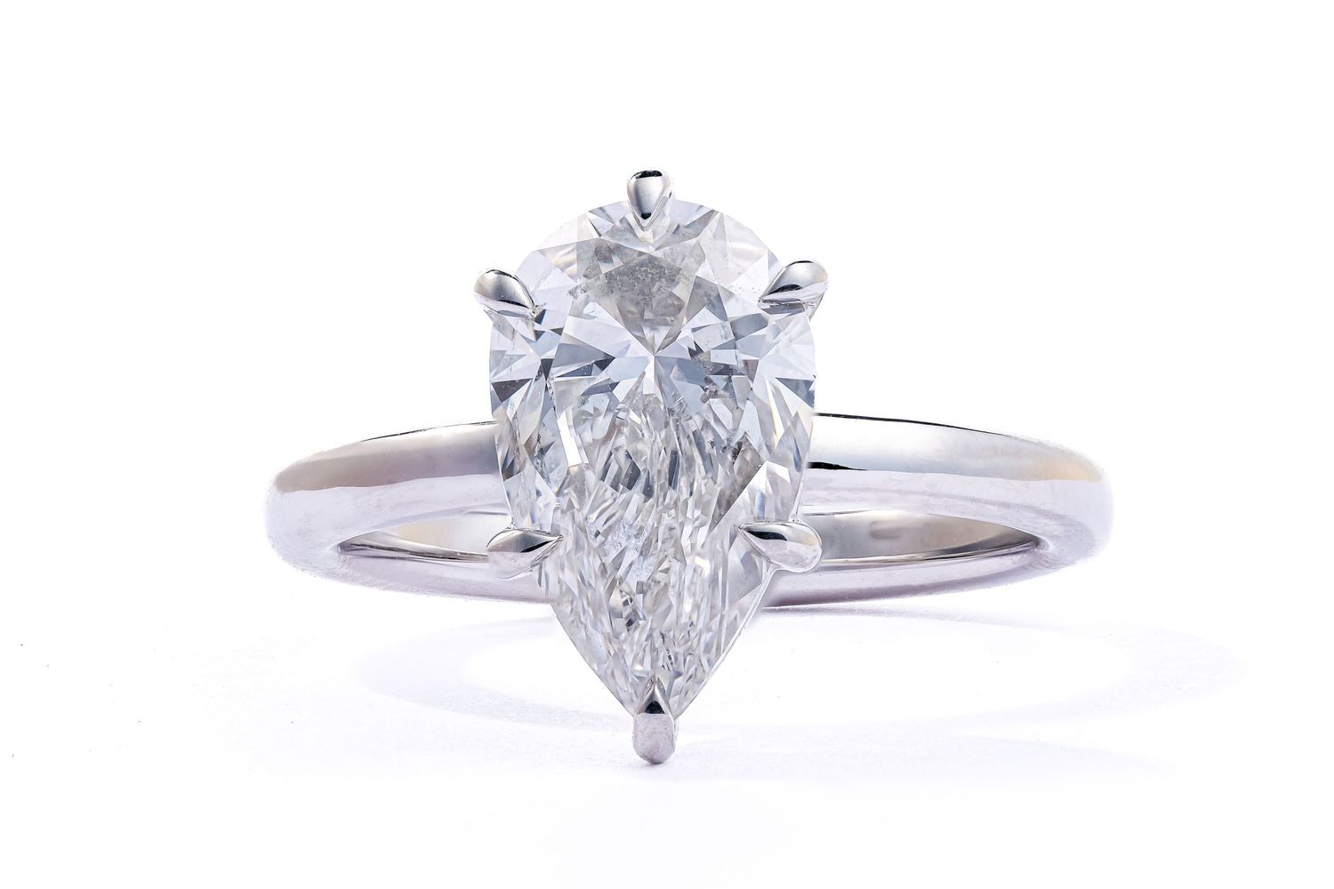 A pear-shaped diamond solitaire engagement ring with a silver band showcases elegant prong settings.