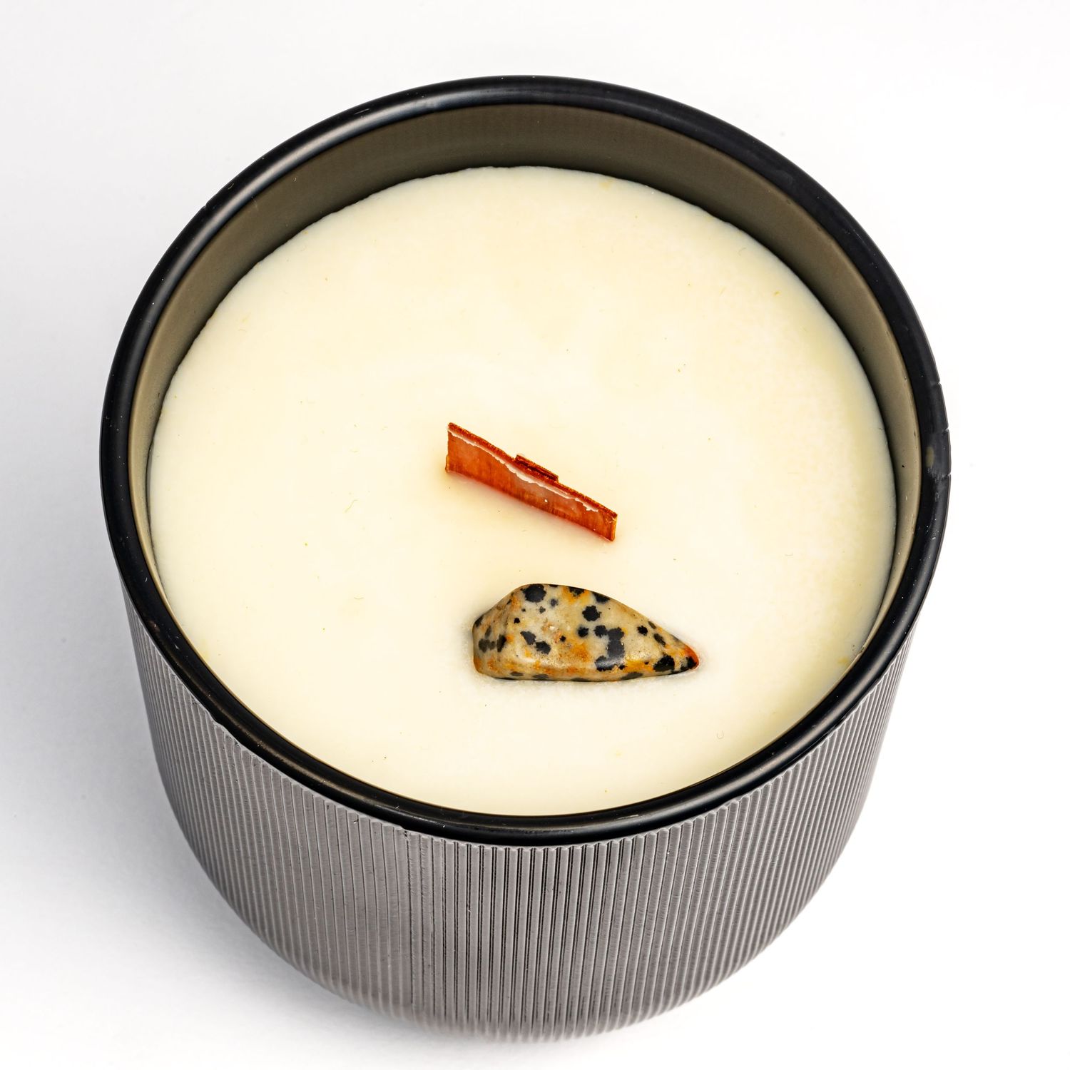 A white scented candle in a gray ridged container with a cinnamon stick and chocolate chip cookie decoration on top.