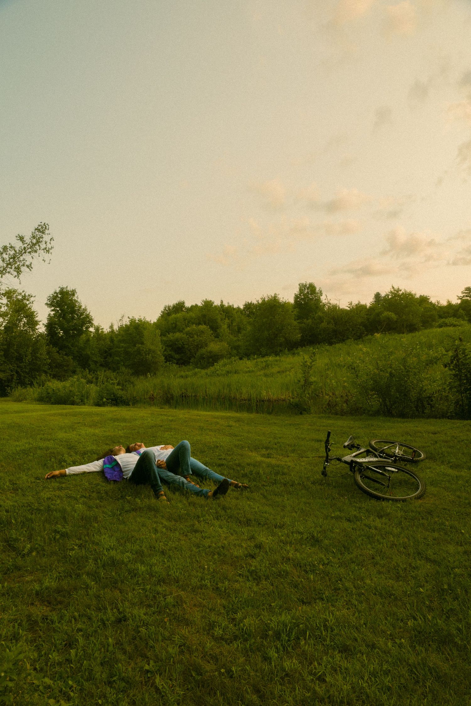 People relaxing on a grassy hillside with bicycles during golden hour.